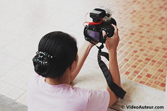 a lady firmly holding a DSLR camera while shooting video