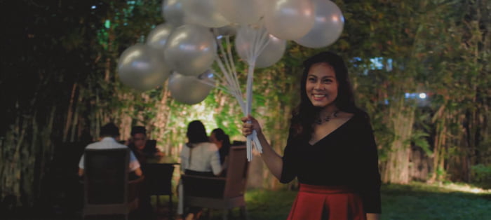 A smiling lady holding some balloons.